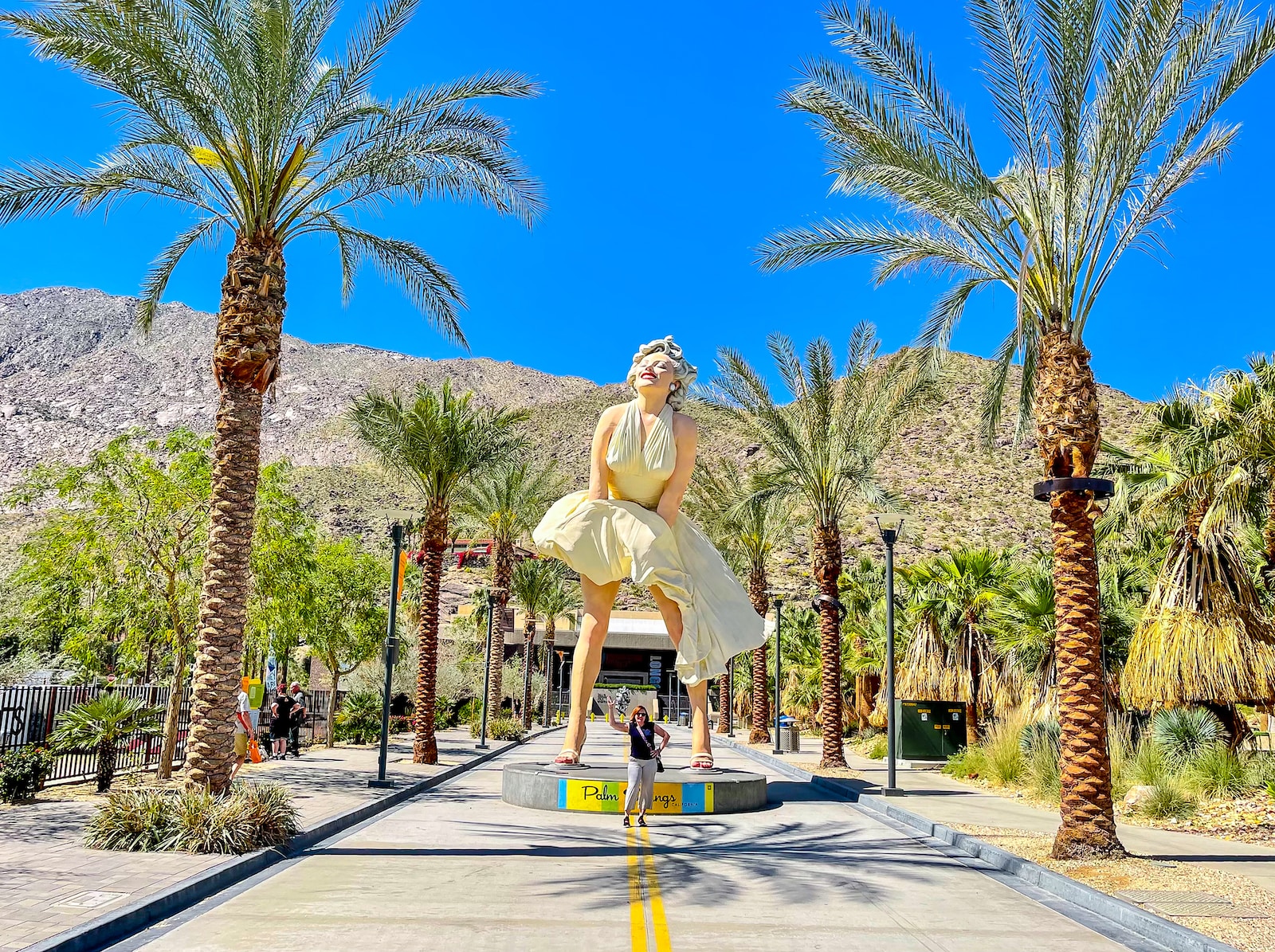 a statue of a person in a dress surrounded by palm trees